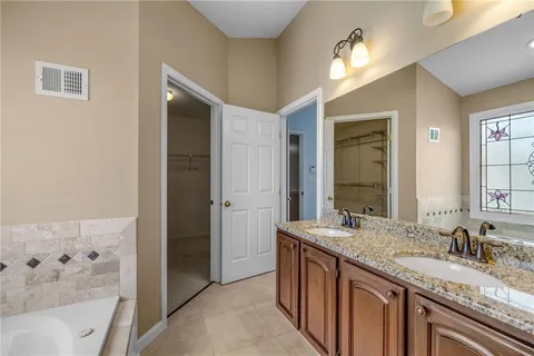 a bathroom with a granite countertop sink a large mirror and a bathtub