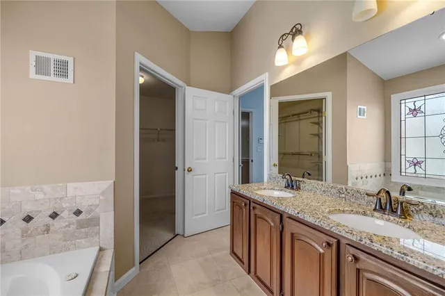 a bathroom with a granite countertop sink a large mirror and a bathtub