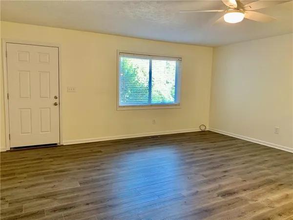 a view of an empty room with wooden floor and a window