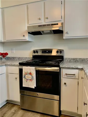 a kitchen with granite countertop white cabinets and stainless steel appliances