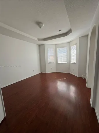 a view of an empty room with wooden floor with a window