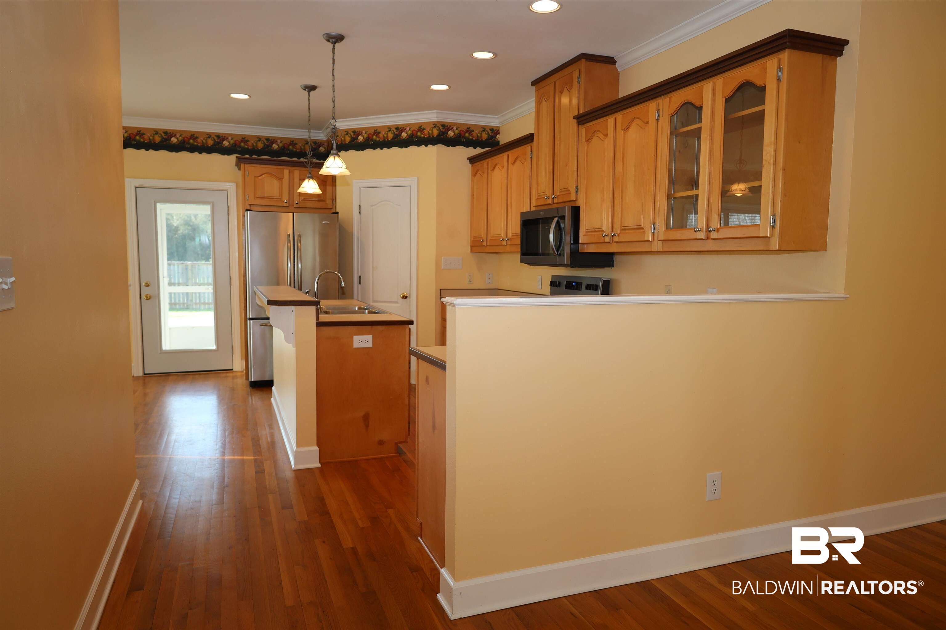 111 Destrehan Road Fairhope, AL 36532 - Photo 5 of 29 Kitchen featuring baseboards, a kitchen island with sink, dark wood-style flooring, glass insert cabinets, and appliances with stainless steel finishes