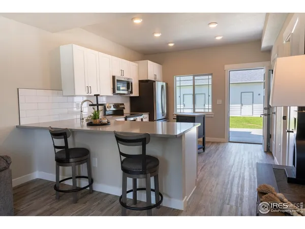 a open kitchen with stainless steel appliances kitchen island granite countertop a table chairs and a refrigerator