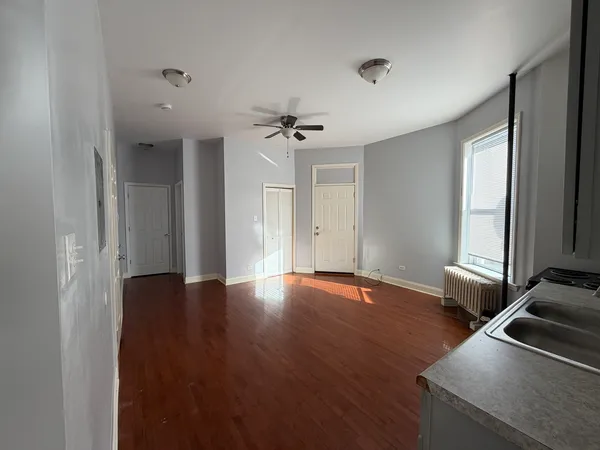 a view of an empty room with a window and wooden floor