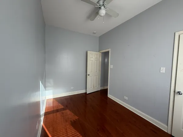 an empty room with wooden floor and fan