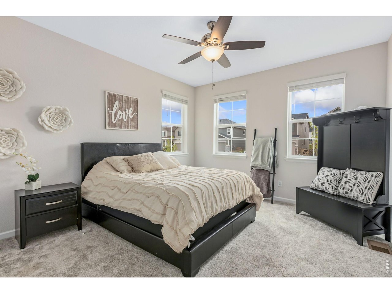 955 Rustling Street Windsor, CO 80550 - Photo 11 of 34 a spacious bedroom with a bed a couch and a flat screen tv