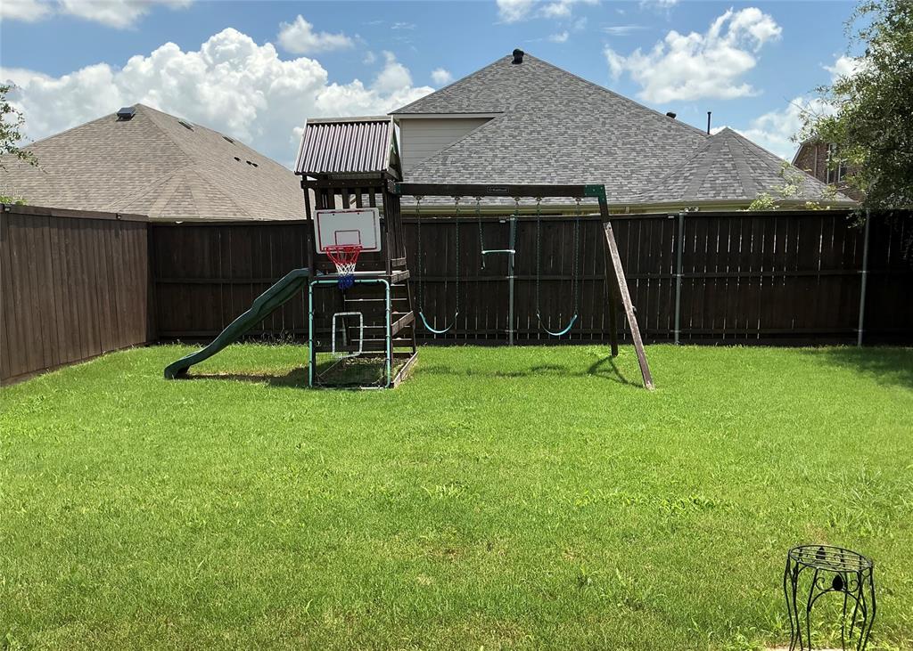 2344 Candler Club Way Little Elm, TX 75068 - Photo 2 of 14 a view of a backyard with a slide and a wooden fence