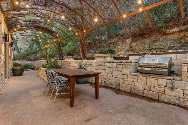 a backyard of a house with barbeque oven table and chairs