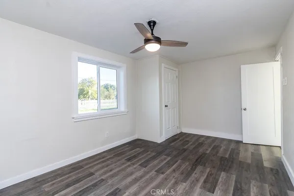 a view of empty room with wooden floor and fan