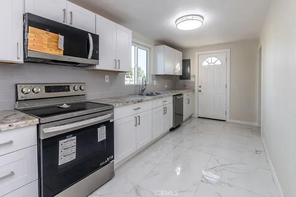a kitchen with stainless steel appliances granite countertop white cabinets a stove top oven a sink and dishwasher