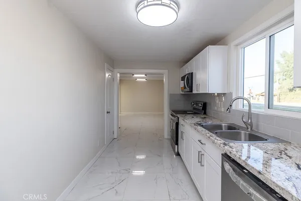 a large kitchen with granite countertop a sink and a stove top oven