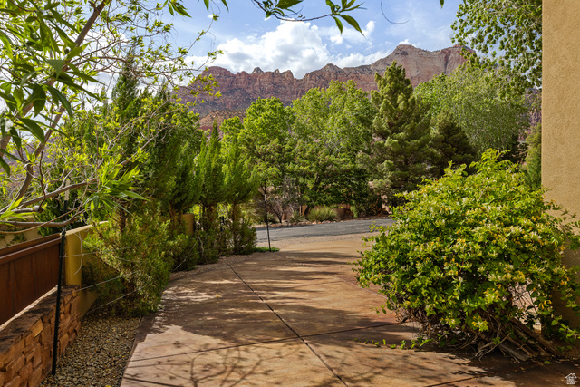 105 River Bend Circle, Unit 105 Springdale, UT 84767 - Photo 41 of 56 Concrete driveway bordered by lush, mature landscaping and a textured stucco exterior