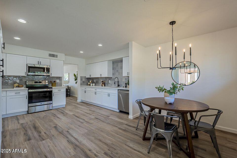 a kitchen with stainless steel appliances a dining table chairs stove refrigerator and cabinets