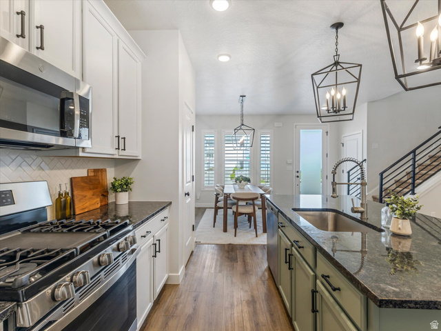 11759 South Watercourse Road South Jordan, UT 84009 - Photo 8 of 33 Contemporary kitchen featuring stainless steel appliances, white shaker cabinetry, dark countertops, a herringbone tile backsplash, and wood-finish flooring