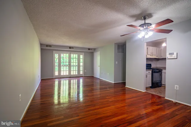 a view of empty room with wooden floor and fan