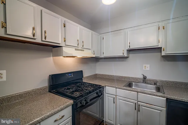 a kitchen with granite countertop white cabinets and a stove top oven