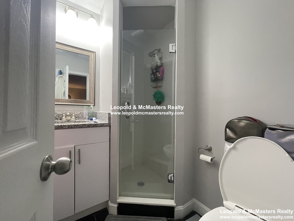 519 Washington Street, Unit 0A Brookline, MA 02446 - Photo 8 of 9 a bathroom with a granite countertop sink mirror and toilet