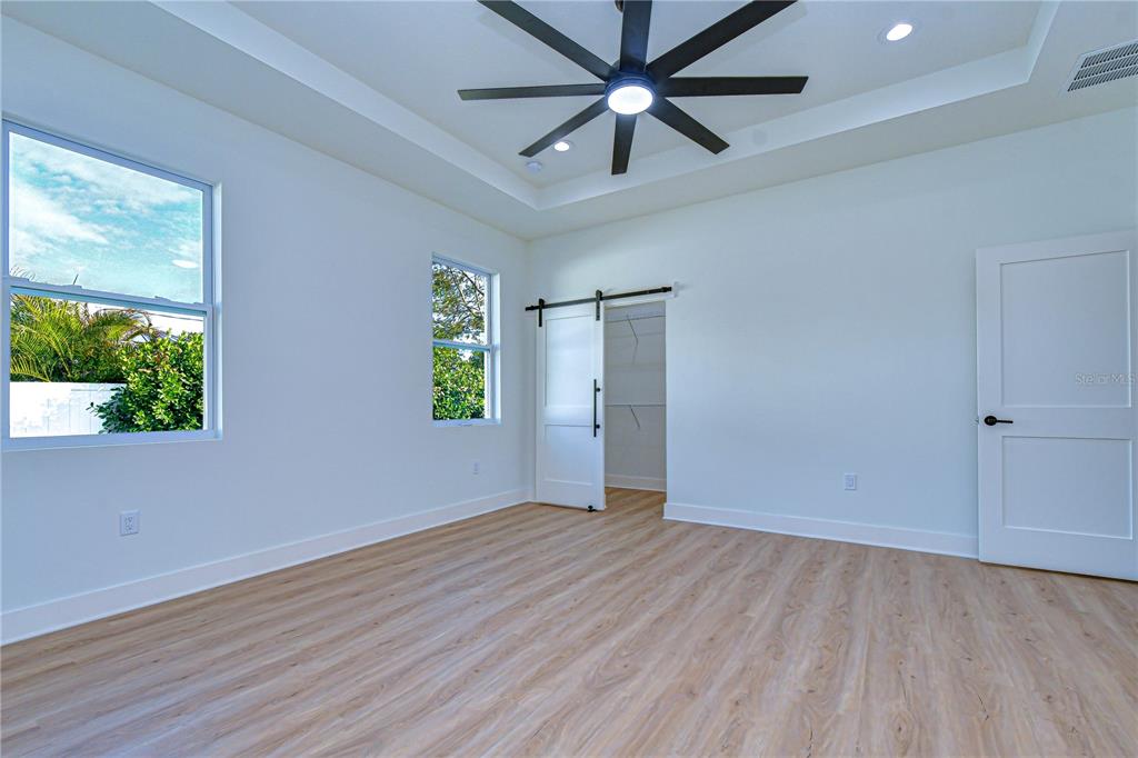 3213 West Aileen Street Tampa, FL 33607 - Photo 13 of 31 an empty room with wooden floor chandelier fan and windows