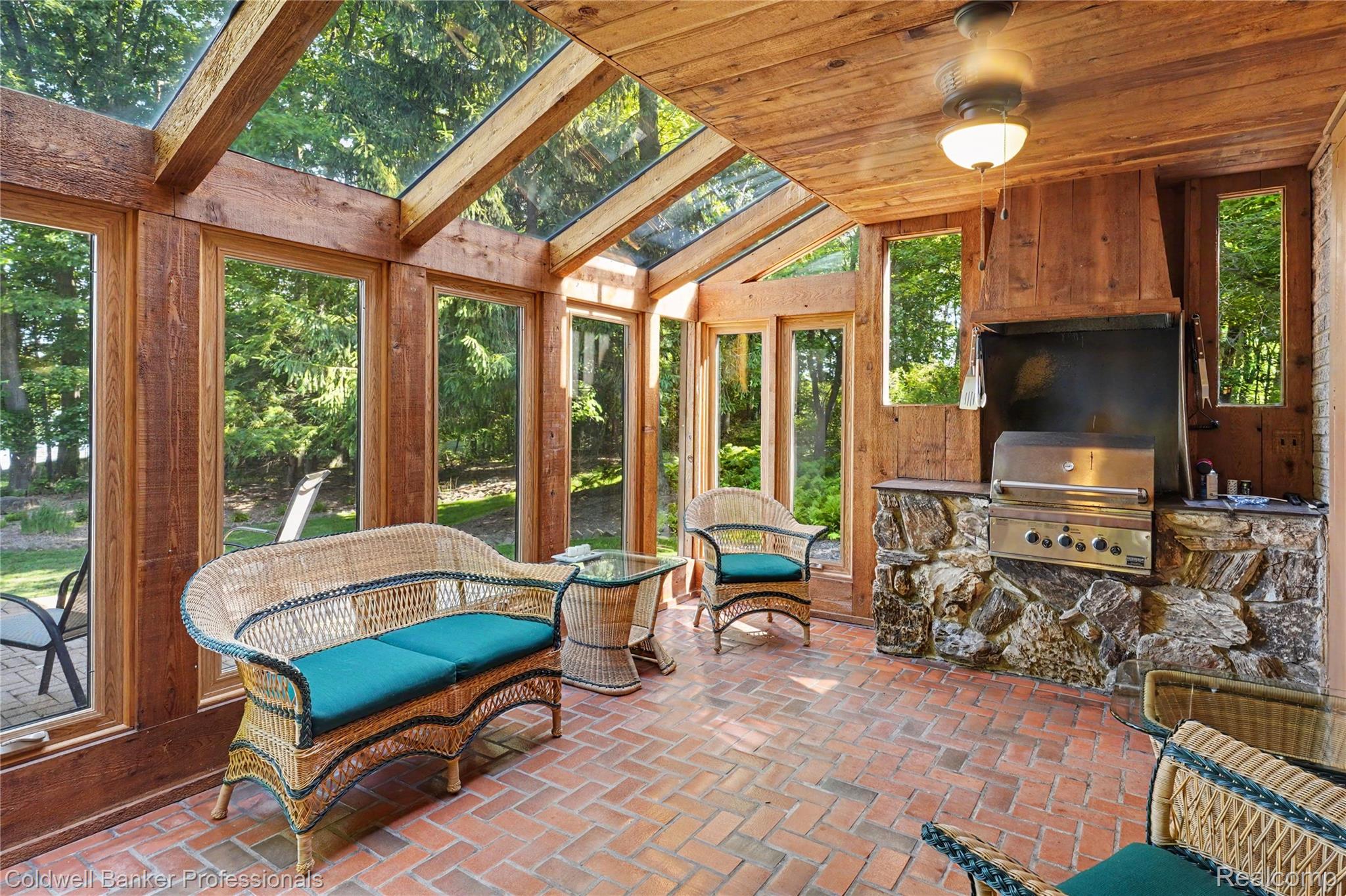 3583 Mitchell Road Metamora, MI 48455 - Photo 23 of 58 Sunroom featuring a built-in outdoor kitchen with a stainless steel grill, stone base, and wood-paneled surround