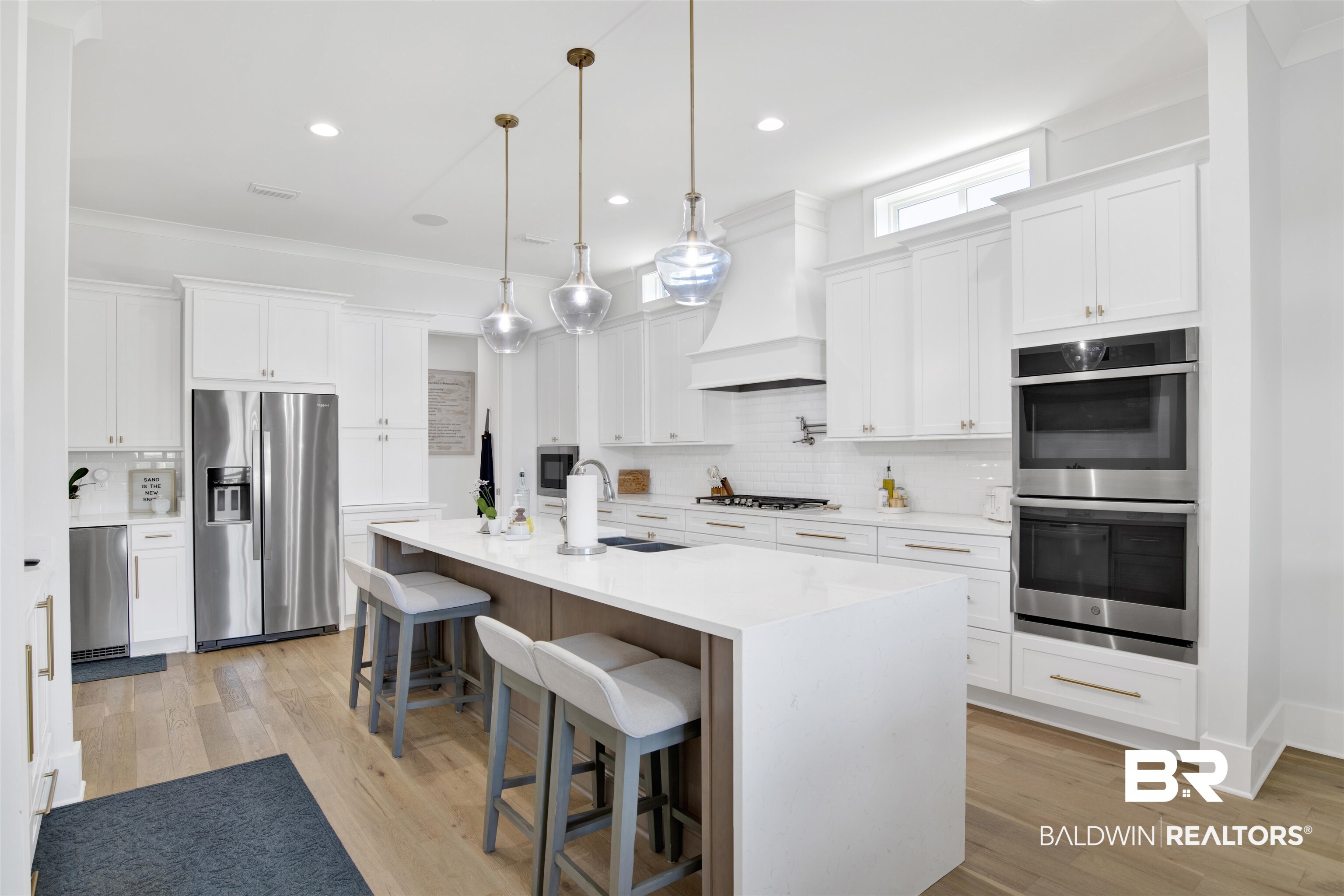 32937 River Road Orange Beach, AL 36561 - Photo 15 of 42 Kitchen featuring premium range hood, a kitchen island with sink, white cabinets, sink, and appliances with stainless steel finishes