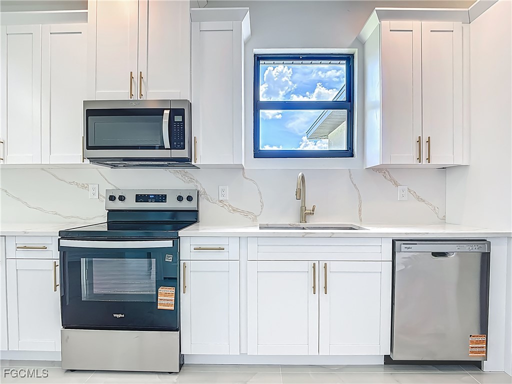 3705 8th Street Southwest Lehigh Acres, FL 33976 - Photo 13 of 34 a kitchen with white cabinets and a stove top oven