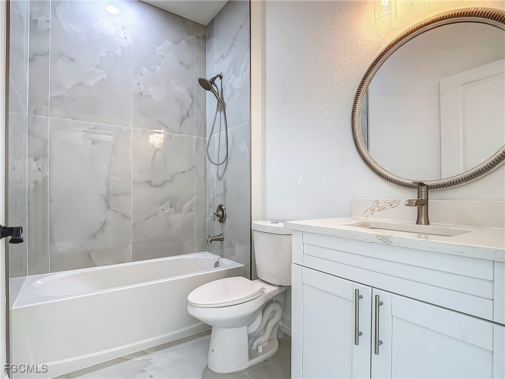 3705 8th Street Southwest Lehigh Acres, FL 33976 - Photo 22 of 34 a bathroom with a toilet a sink a mirror and bathtub