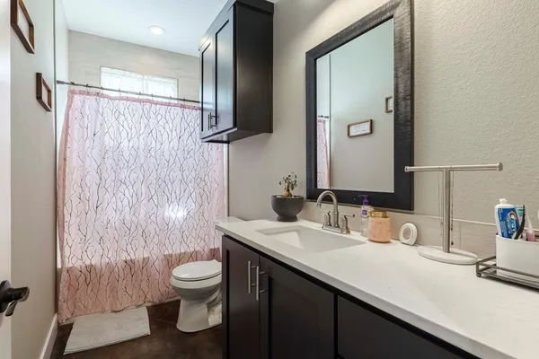 a bathroom with a granite countertop sink toilet a mirror and shower curtain