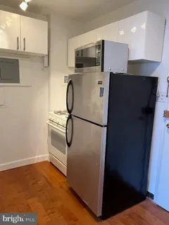 a view of kitchen with stainless steel appliances wooden floor and staircase