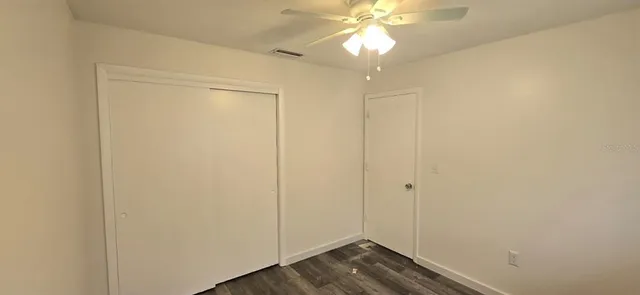 an empty room with wooden floor and fan