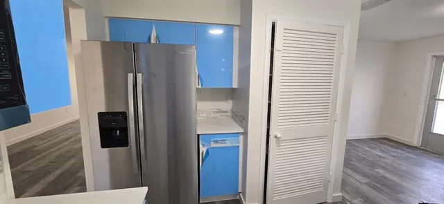 a view of a kitchen with refrigerator and wooden cabinets