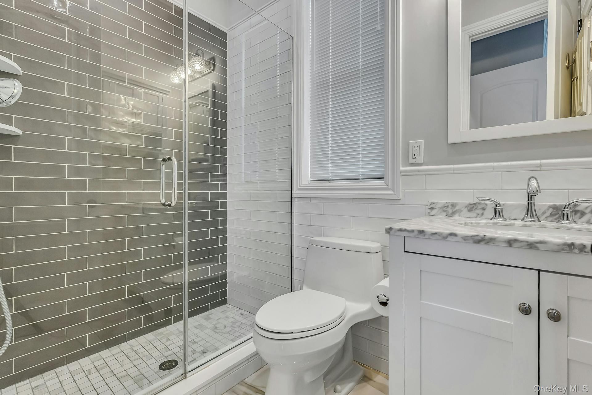2 Seaman Road Glen Cove, NY 11542 - Photo 11 of 17 Custom primary bath with stall shower, rain head and handheld shower head, vanity and mirror.