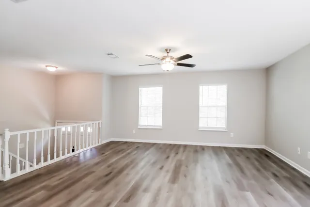 a view of an empty room with a window and wooden floor