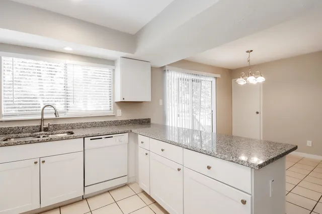a kitchen with white cabinets and window