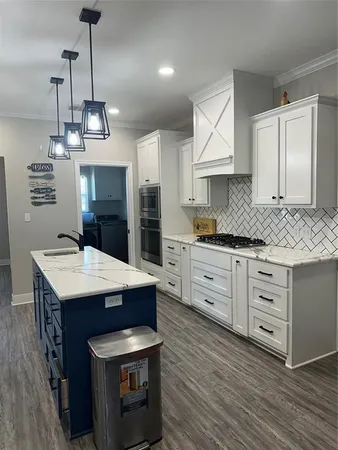 a kitchen with kitchen island granite countertop a sink cabinets and wooden floor
