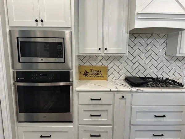 a kitchen with granite countertop white cabinets and stainless steel appliances
