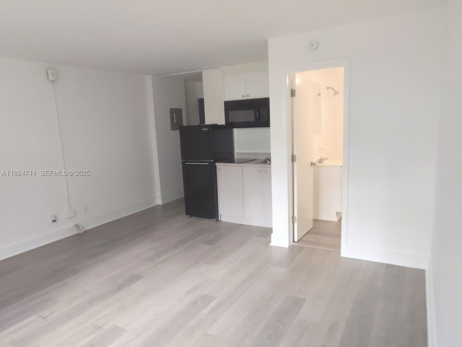 143 Southwest 9th Street, Unit 203 Miami, FL 33130 - Photo 3 of 9 a view of a kitchen with refrigerator and wooden floor