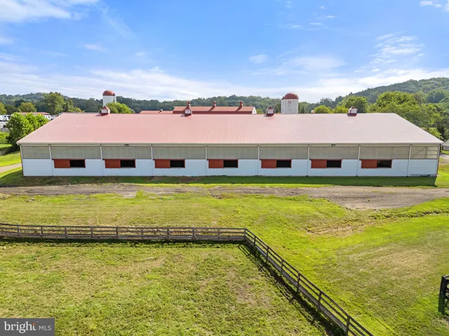 an aerial view of a tennis ground and a cars park side of the road