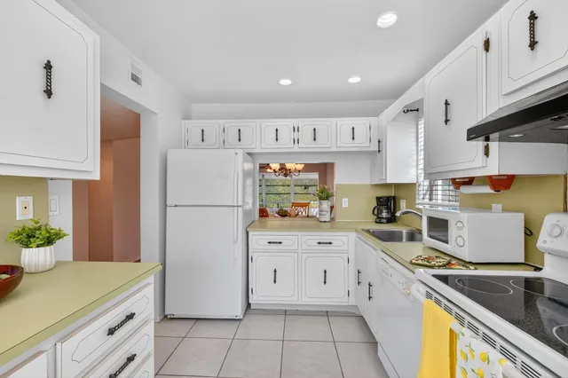 a kitchen with a refrigerator a stove a sink dishwasher and white cabinets with wooden floor