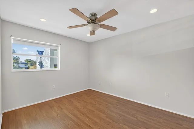 an empty room with wooden floor and ceiling fan