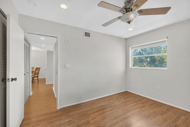 an empty room with wooden floor fan and windows