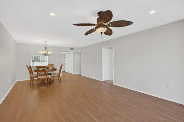 a dining room with wooden floor a chandelier a wooden table and chairs