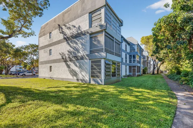 a view of a big building with a big yard and large trees