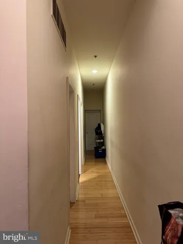 a view of a hallway with wooden floor and a bathroom