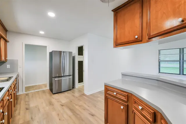 a kitchen with stainless steel appliances granite countertop a refrigerator a stove and a sink with wooden floor