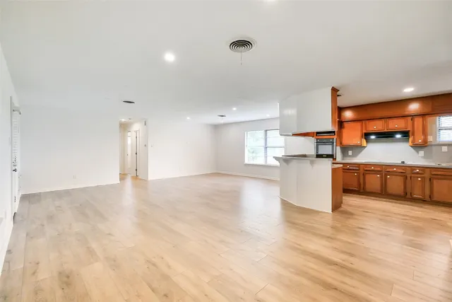 a view of kitchen with kitchen island a sink wooden floor and stainless steel appliances
