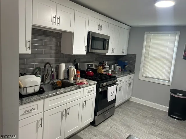 a kitchen with granite countertop white cabinets and black appliances