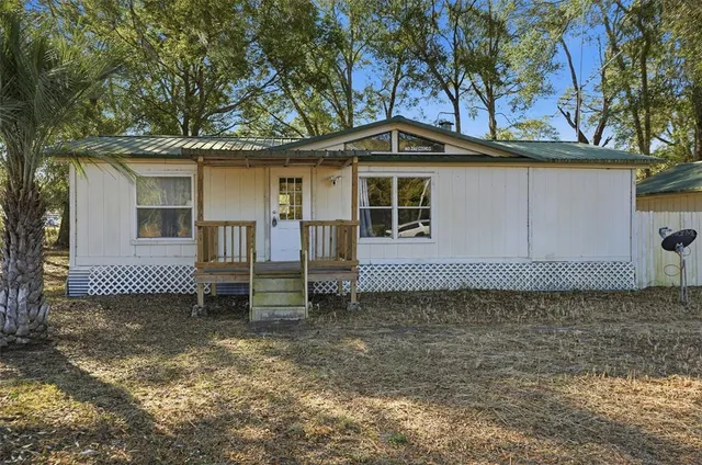 a backyard of a house with lawn chairs and a large tree