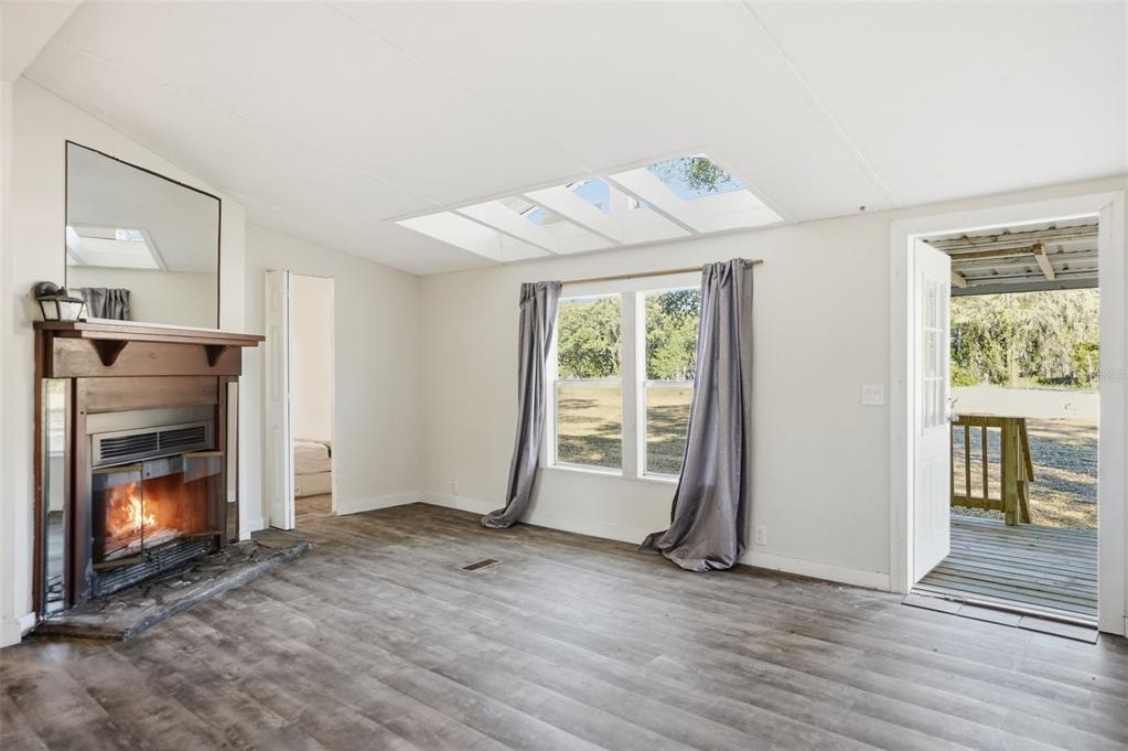 25256 Richbarn Road Brooksville, FL 34601 - Photo 5 of 32 an empty room with wooden floor fireplace and windows