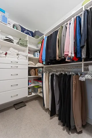 a view of walk in closet with clothes and shoes