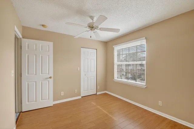 an empty room with windows and fan